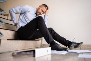 preexisting injuries affect personal injury cases-man sitting on stair with binders and paper surrounding him.
